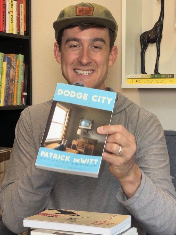 Will Pass holding Dodge City by Patrick deWitt, his favorite book from July